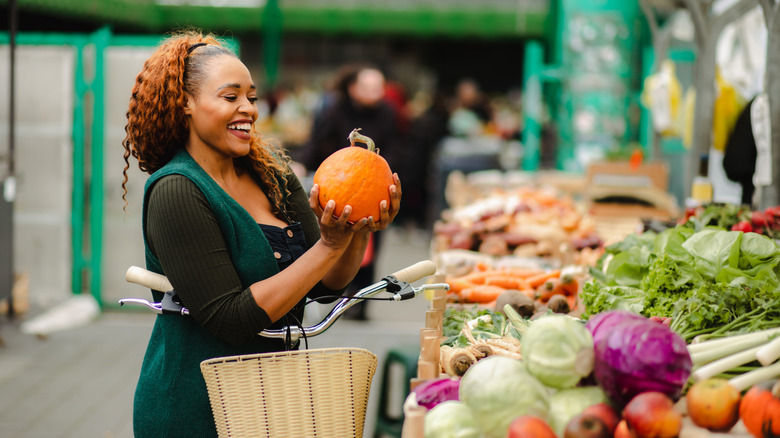 woman picking up squash at market
