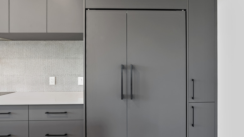 Refrigerator finished with gray panels and black hardware to match surrounding kitchen cabinets