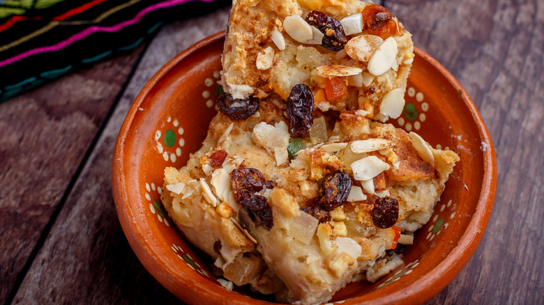 Bowl of capirotada bread pudding with raisins and sliced almonds
