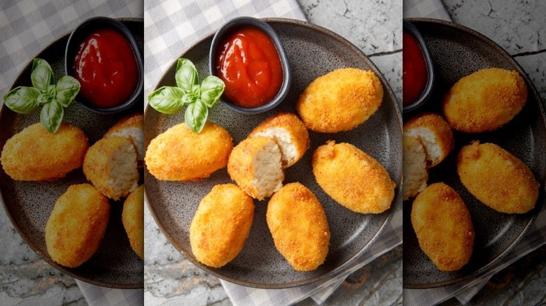 An overhead shot of a ceramic plate of croquetas with dipping sauce