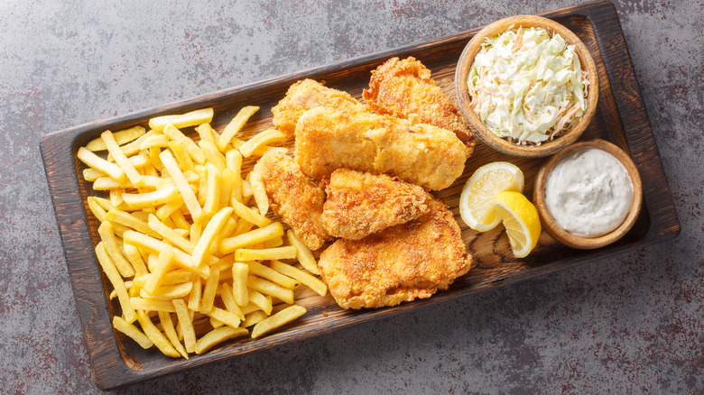 A close-up of a person pouring beer from a long line of taps, with full glasses of beer in the foreground