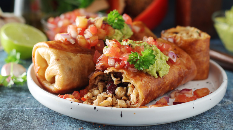 Chimichangas topped with guacamole and tomatoes