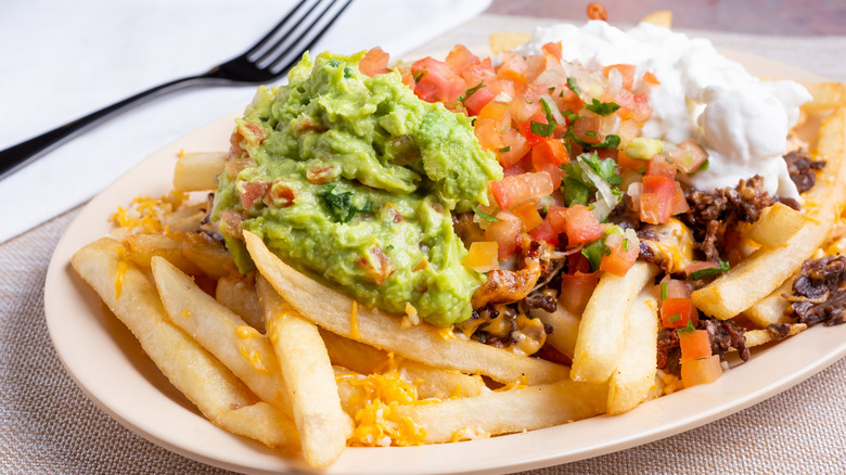 Fries topped with guacamole and tomatoes