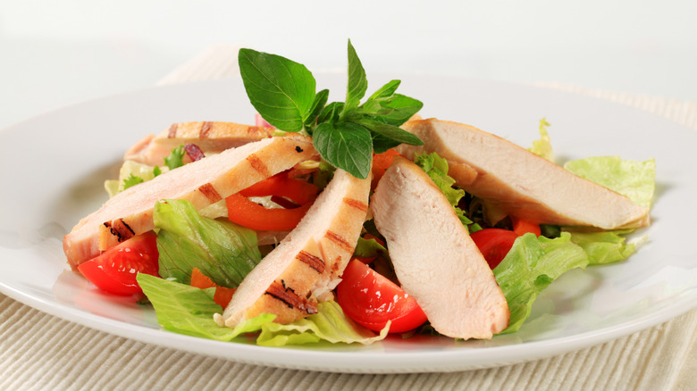 Slices of grilled chicken meat on salad