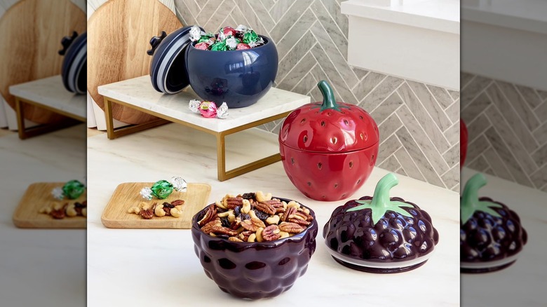 Three berry shaped containers filled with various treats and snacks.