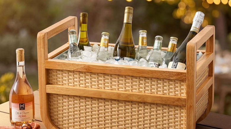 A woven basket drink cooler with multiple bottles on ice.