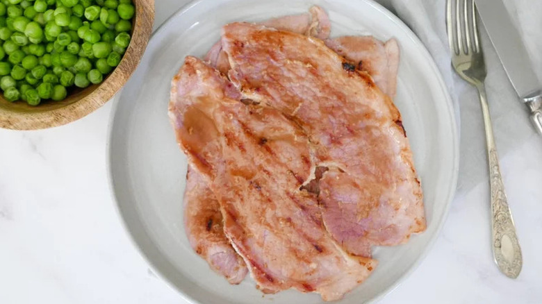 Ham steaks with a glaze and peas on the side