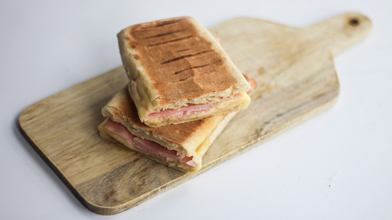 Halved ham and Swiss panini on a cutting board