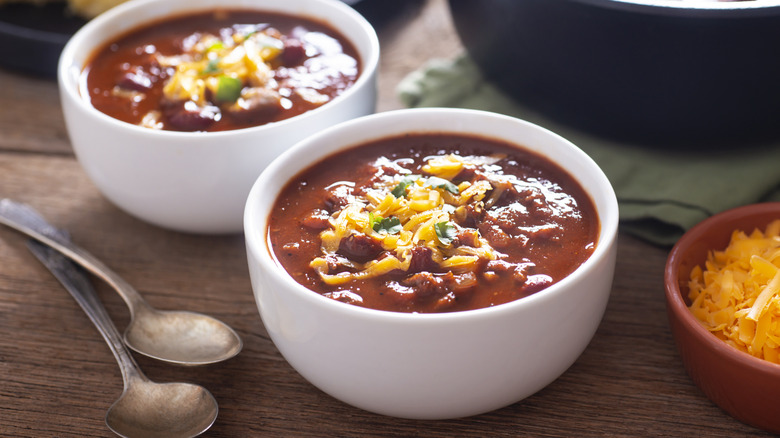 two bowls of chili with shredded cheese