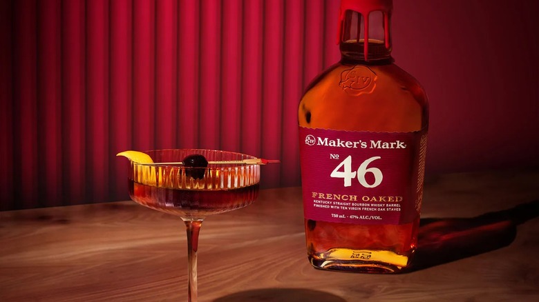 Bottle of Maker's Mark 46 French Oak Bourbon on table with cocktail