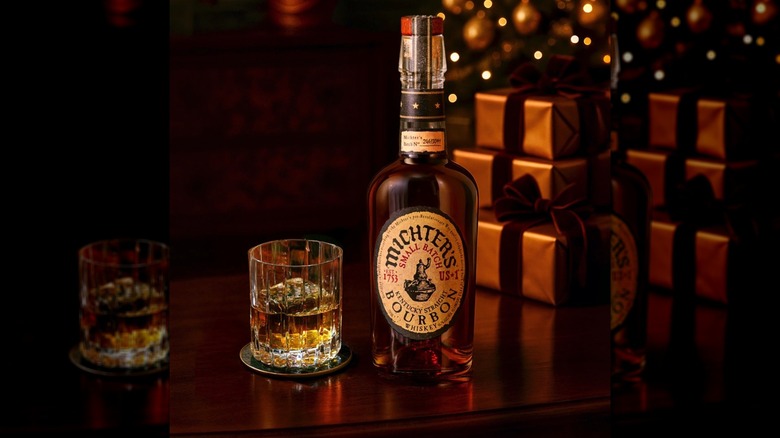 Bottle and glass of Michter's Small Batch Kentucky Straight Bourbon with wrapped gifts in background