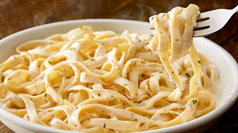 Close-up of a fork digging into a dish of Olive Garden Fettuccine Alfredo