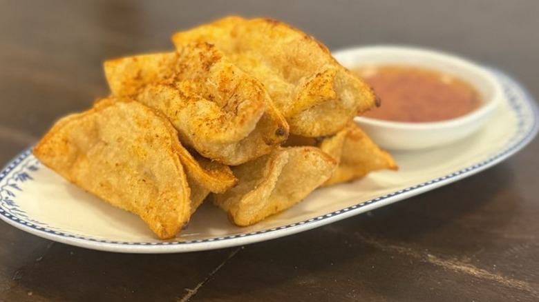 Five fried crawfish dumplings on plate with side of sauce at Good Fortune Co. Restaurant