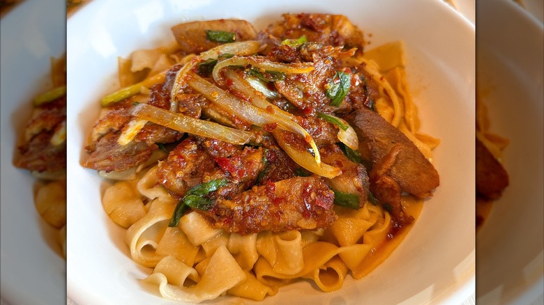 Dish of meat seasoned with pepper sauce over hand-pulled noodles at Blue Koi restaurant