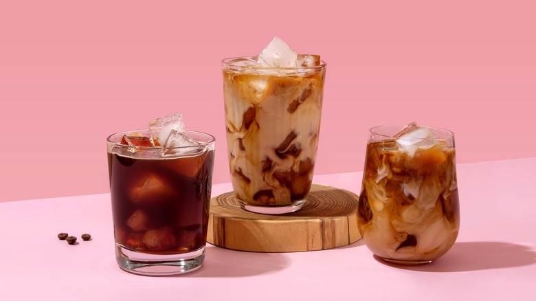three glasses of iced coffee on a pink background