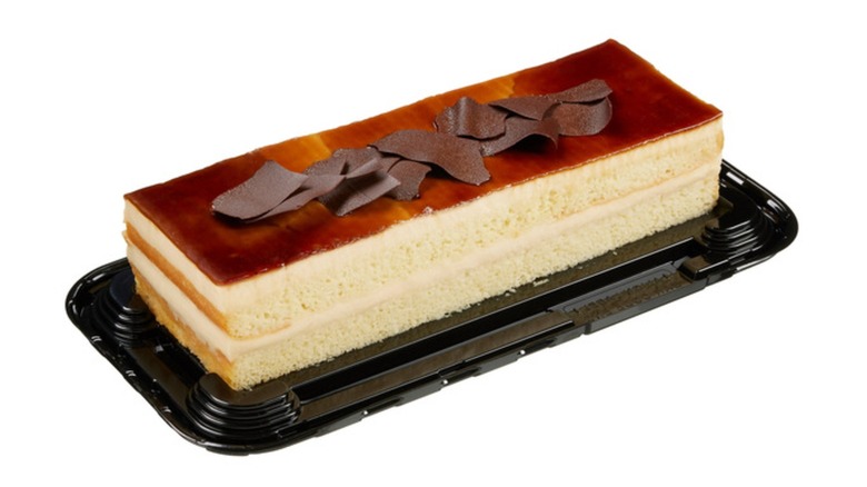 Picture of a bar cake topped with caramel on black platter on a white background