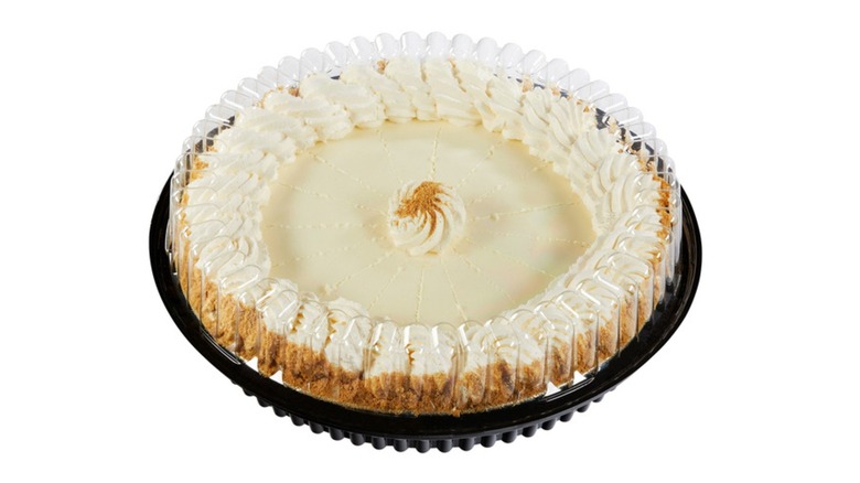 Key lime pie in a black pie tin topped with a plastic lid