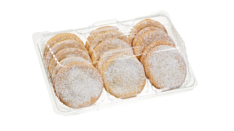 Sugar cookies topped with powder sugar in a plastic clamshell container