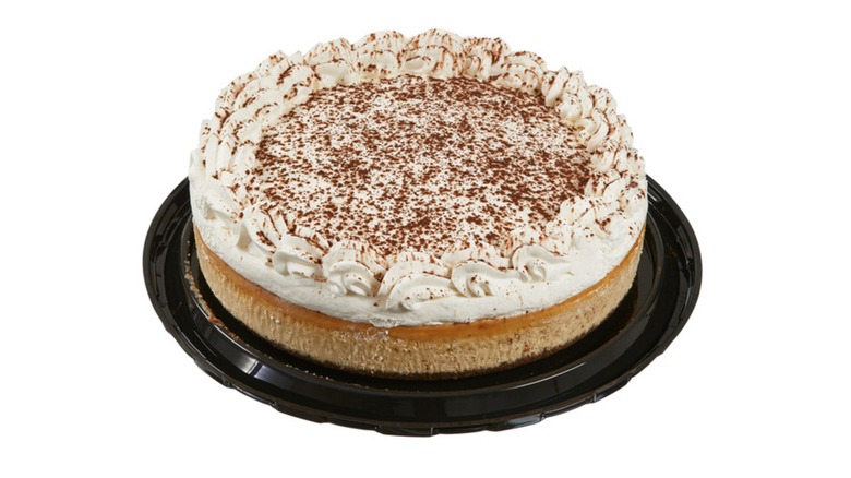 Picture of a tiramisu cheesecake on a black platter on a white background