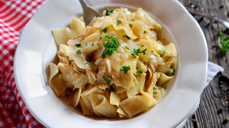 depression era cabbage pasta  sprinkled with parsley in white bowl with fork