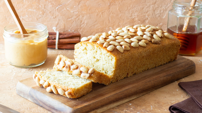 peanut butter bread sliced on cutting board with peanut butter and honey in separate jars