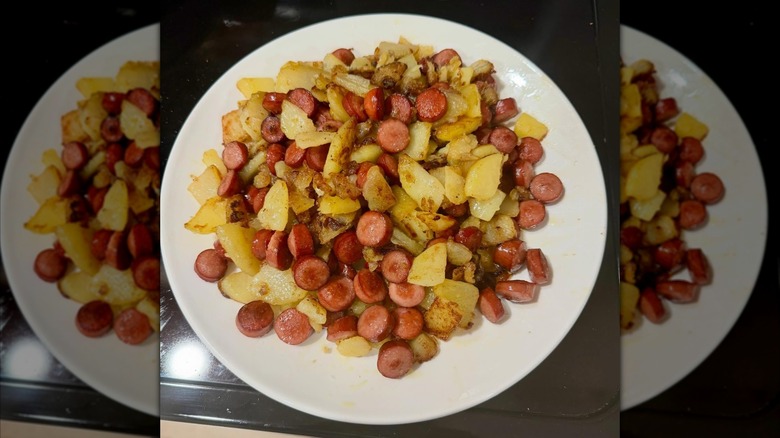 poor mans meal with hot dogs potatoes and onion on white plate