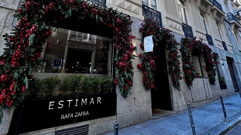 The entrance of Estimar in Barcelona showing the logo and flowers around the doors and windows