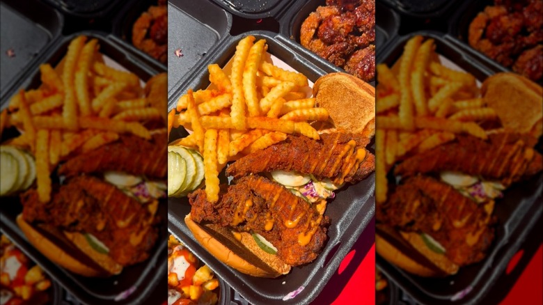 Fried chicken sandwich and french fries in a black takeout container