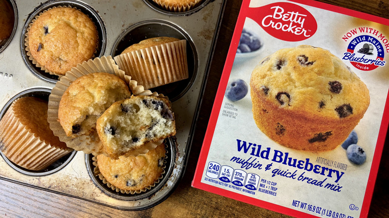 A box of Betty Crocker Wild Blueberry muffin mix and baked muffins in a muffin pan