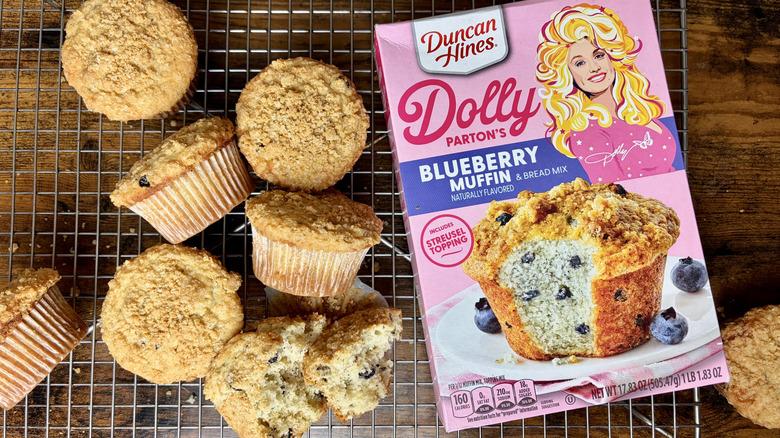 A box of Dolly Parton's Blueberry Muffin & Bread Mix with several baked muffins
