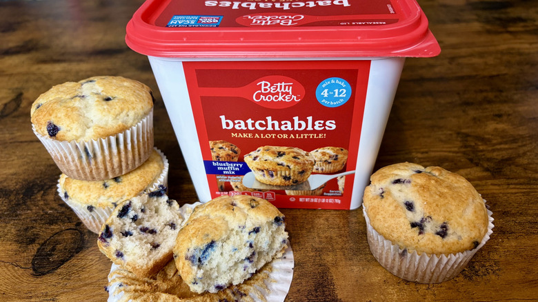 A container of Betty Crocker Batchables blueberry muffin mix and four baked muffins