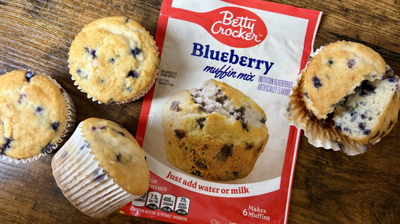 A package of Betty Crocker Blueberry muffin mix and baked muffins