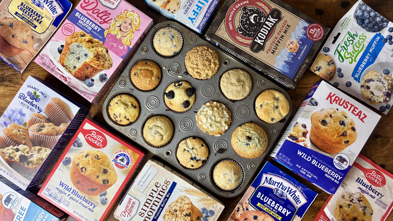 13 boxes of blueberry muffin mix with a pan of freshly baked blueberry muffins