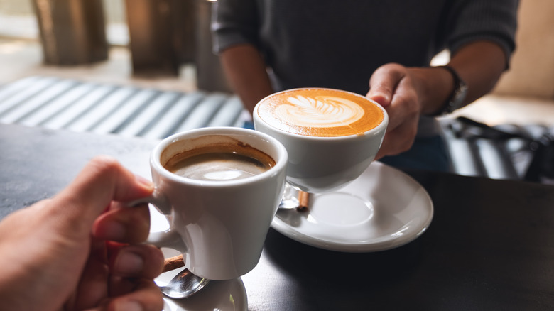 holding two hot drinks