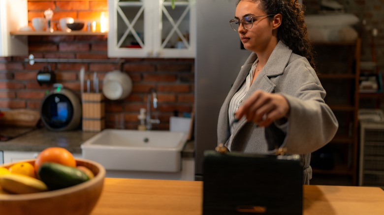 woman putting handbag down on kitchen counter