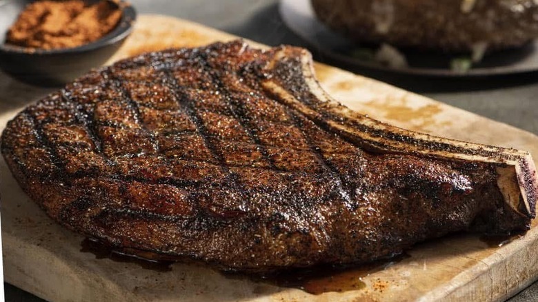 Outlaw Ribeye on a wooden board with spices in background
