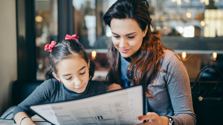 Mother and daughter looking at kids menu