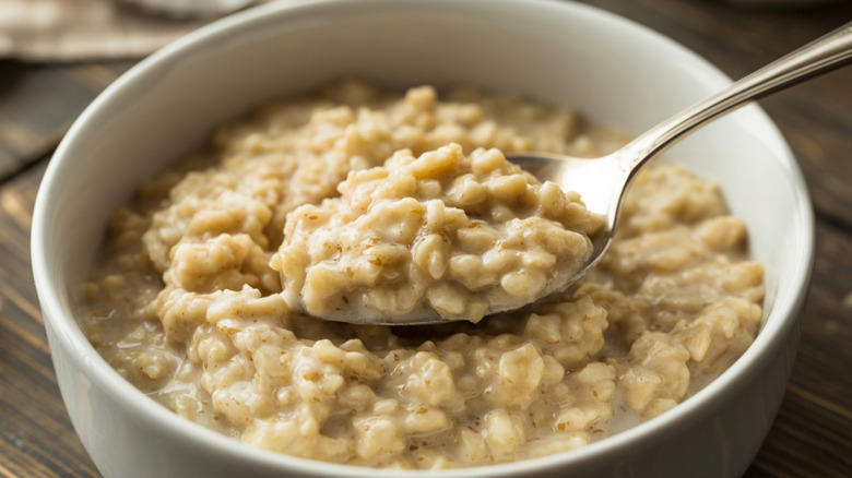 A close-up of a bowl of oatmeal with a spoon scooping up a bite