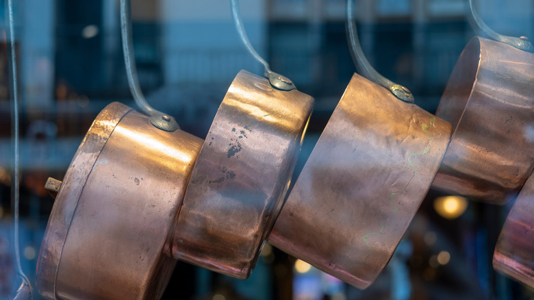 four to five hanging bronze pans in front of a glass window