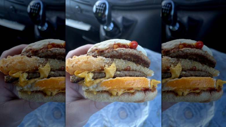 Hand holding a breakfast sandwich from McDonald's with a hash brown inside