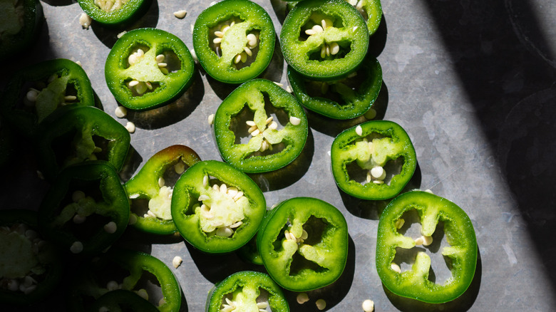 Sliced jalapenos with seeds on a gray countertop