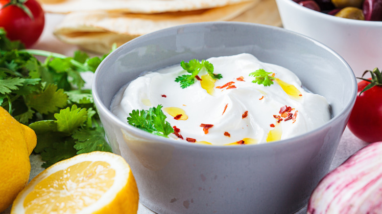 Gray bowl of whipped feta cheese topped with oil, herbs, and spices