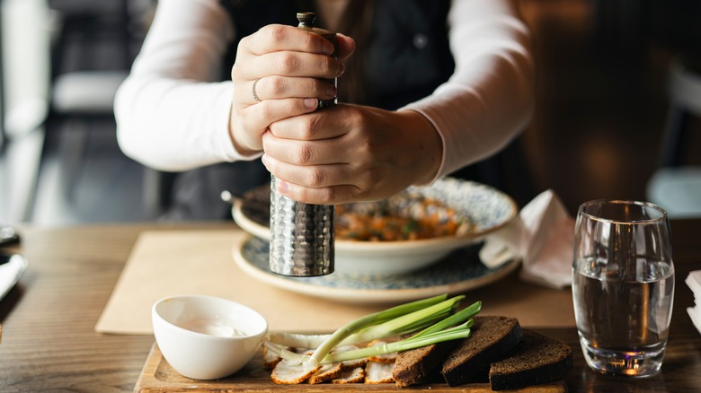 Hands holding pepper grinder