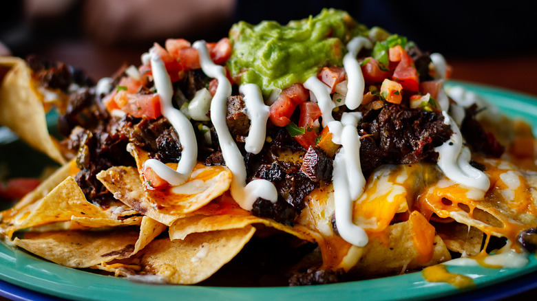 nachos topped with guacamole, sour cream, beef and cheese
