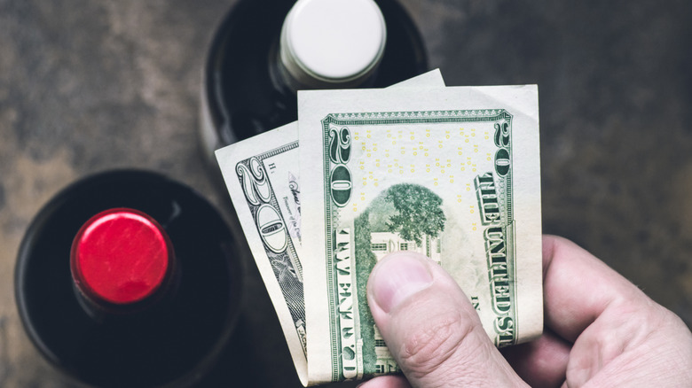 Person paying cash for wine