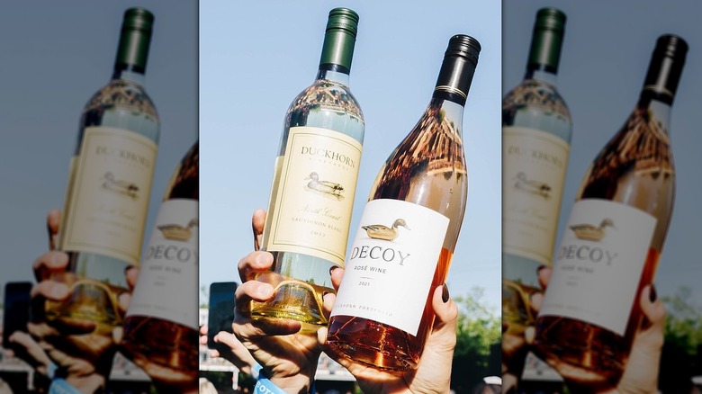 Hands holding bottles of Duckhorn and Decoy wine
