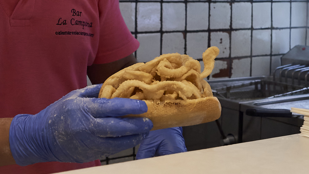 Man holding fried calamari on a roll