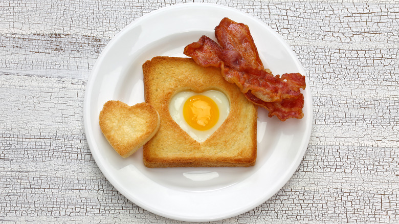 fried egg baked in fried bread with heart cutout and bacon