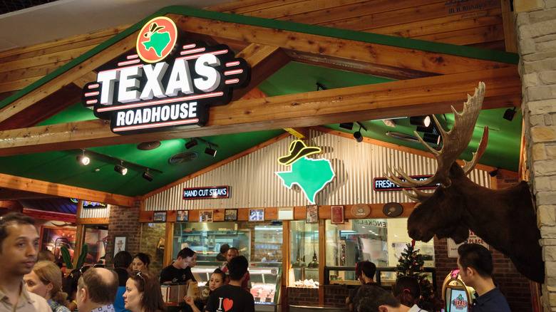 People milling around Texas Roadhouse, kitchen in background