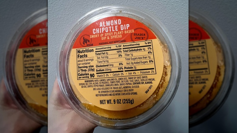 Hand holds a container of Trader Joe's Almond Chipotle Dip